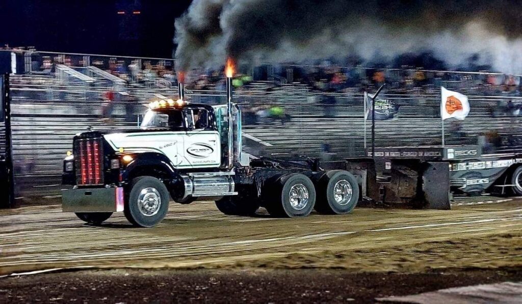 Black Semi-Truck Competing in Sled Pulling at a Nighttime Truck Racing Event